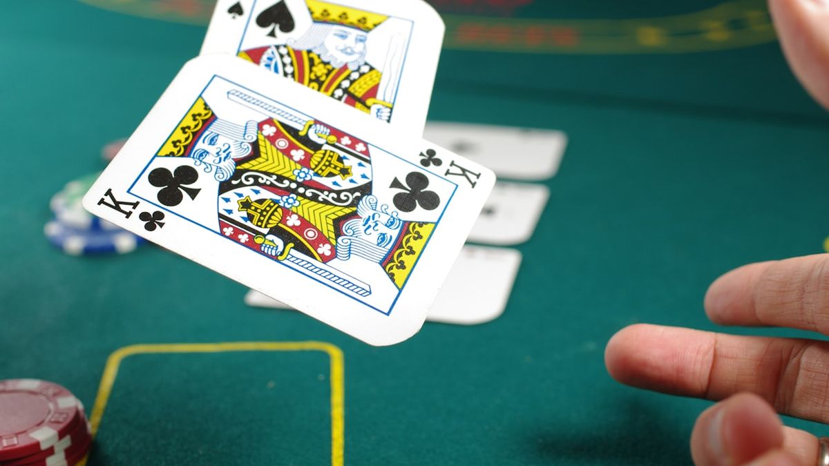 Tangan memegang dua kartu king dan ace di meja poker